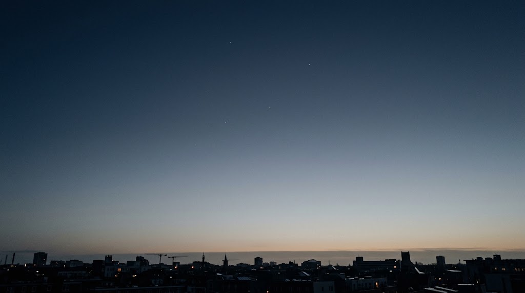 夜明け前の空に薄く残る星と、地平線の光